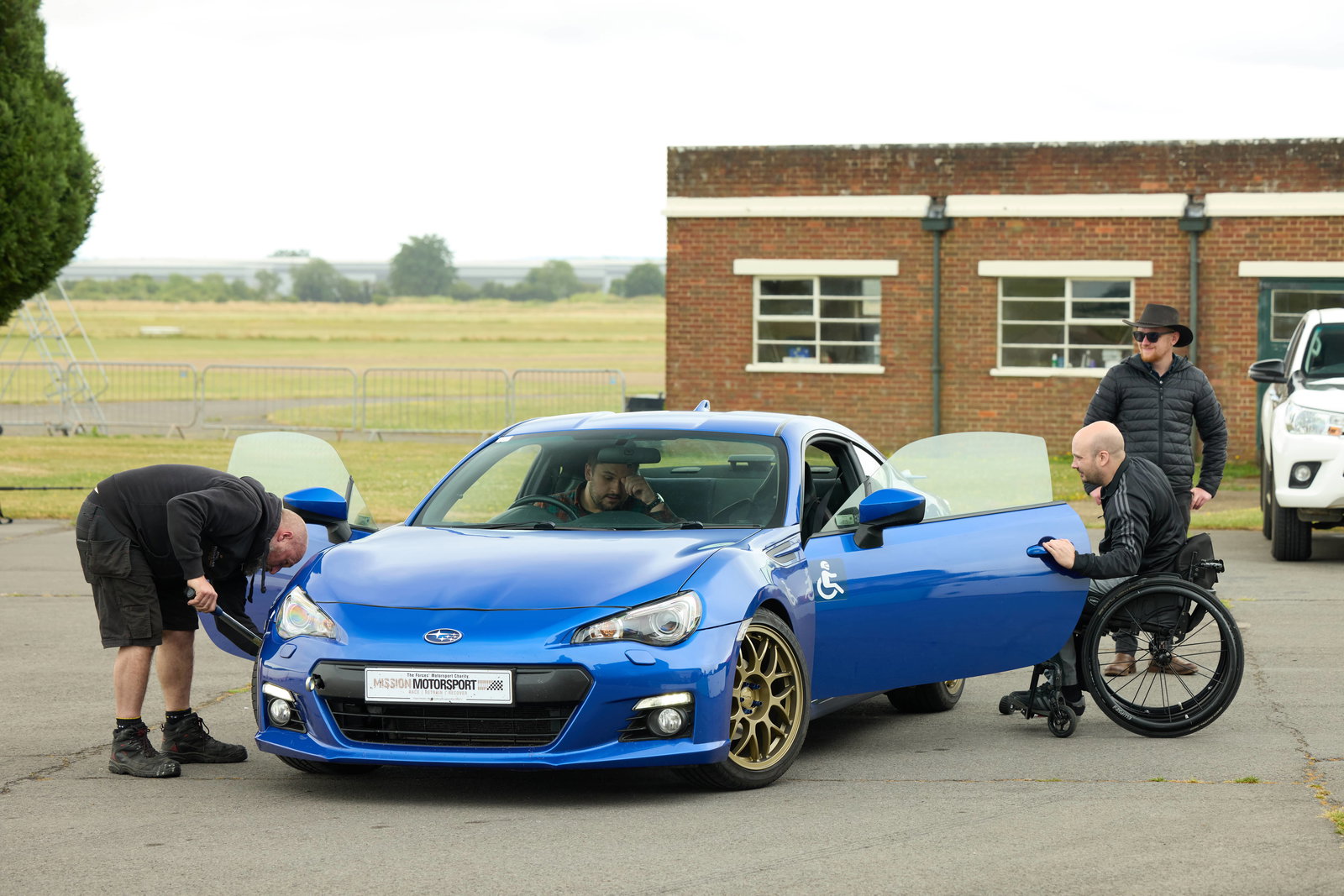 MM workshop manager Aston Dimmock adjusts tyre pressures while beneficiary Dom Pearson prepares to get in the car